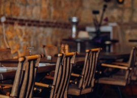 Rustic restaurant interior with empty wooden chairs set against a stone wall, creating a cozy dining atmosphere.