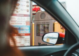 Blurred driver choosing food from menu and telling order to drive thru speaker post