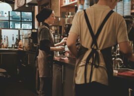 Baristas at work in a cozy cafรฉ, using coffee machines to prepare drinks.